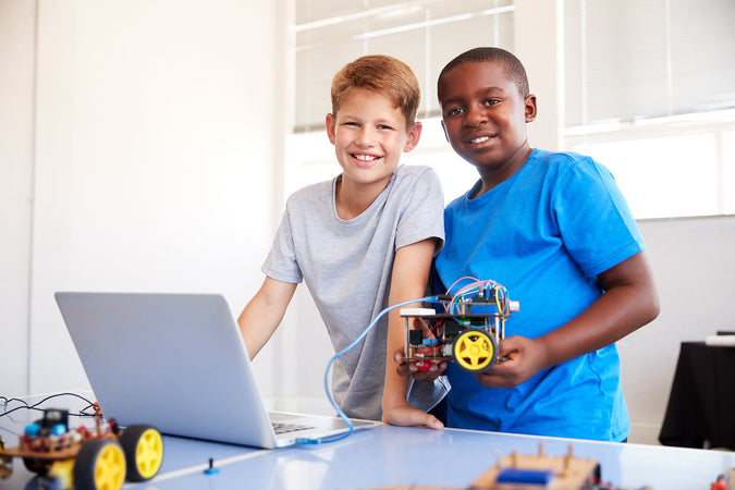 Coding camps for kids - Two Male Students Building And Programing Robot Vehicle